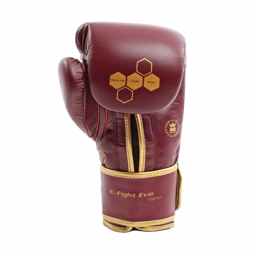 Gant de boxe bordeaux Montana X-FIGHT Evo Legend vu de trois quarts, montrant les hexagones dorés sur le dessus, le passepoil doré et l'ouverture de la manchette.