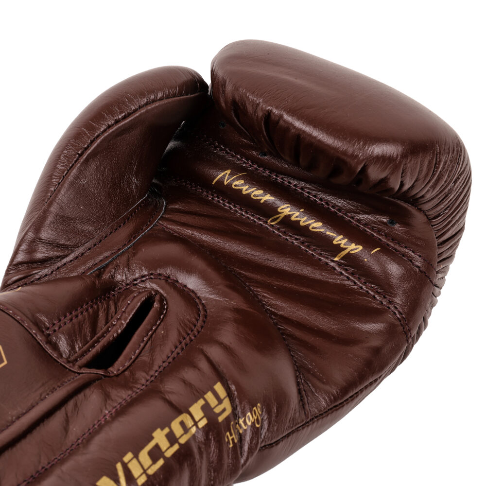 Détail macro du gant de boxe Montana VICTORY Heritage : cuir marron patiné, marquage Victory doré et inscription Never give-up sur la manchette.