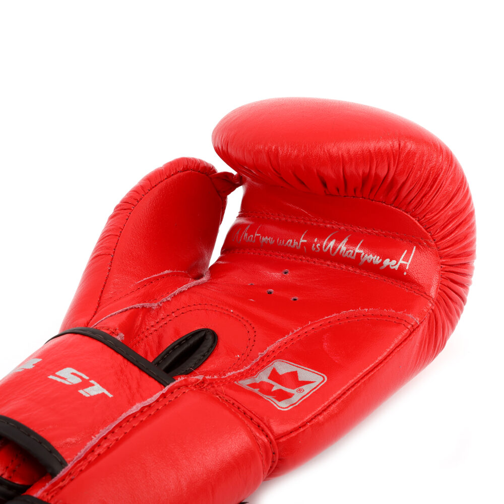 Détail macro du gant de boxe Montana 34ST NewCode : texture du rouge, inscriptions blanches sur la manchette et étiquette de la marque.