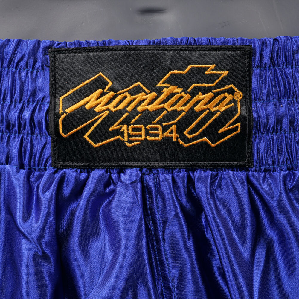 Détail de la ceinture du short de boxe Montana MUAY THAI NewCode : logo Montana 1934 brodé en doré sur la large bande élastique bleue.