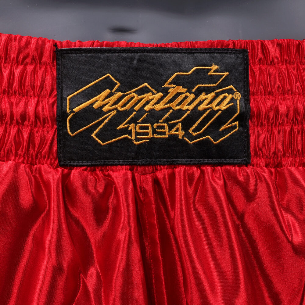 Détail de la ceinture du short de boxe Montana MUAY THAI NewCode : logo Montana 1934 brodé en doré sur la large bande élastique rouge.