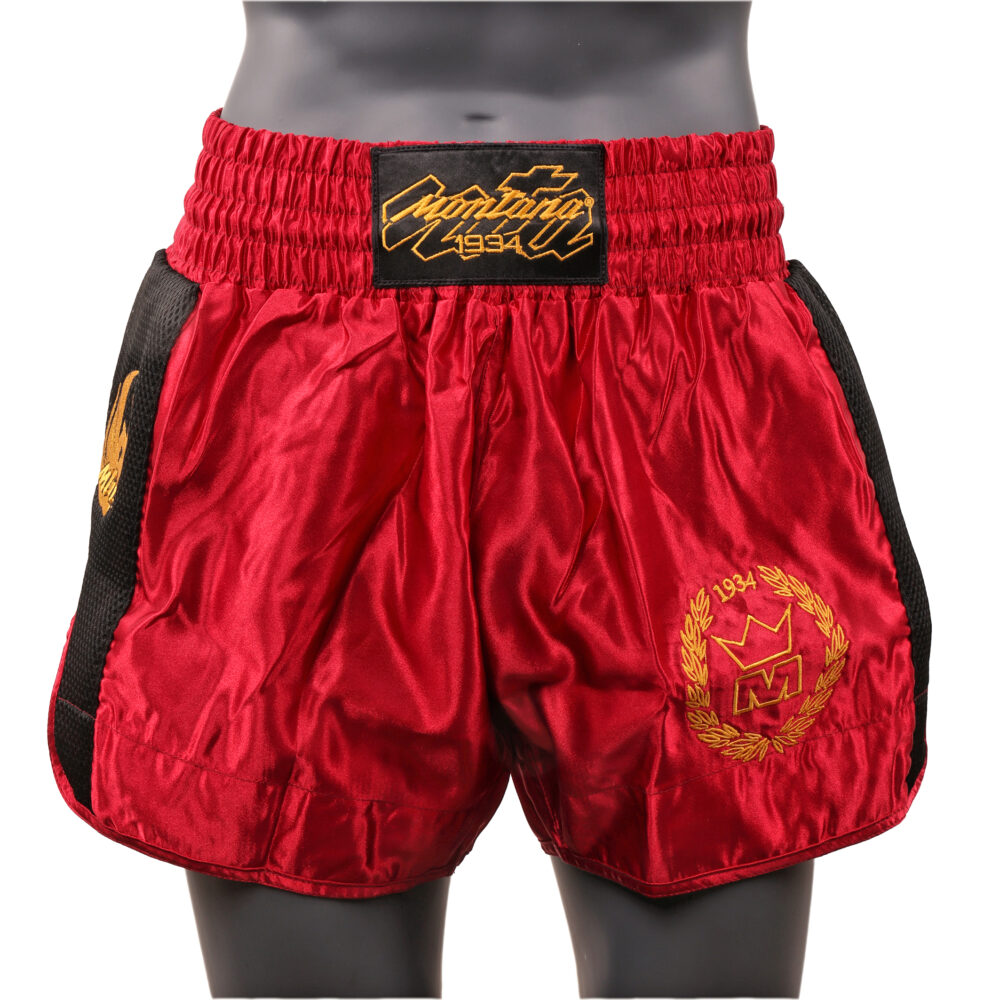 Short de boxe bordeaux Montana MUAY THAI NewCode Legend en satin polyester, porté et vu de face, avec la large bande élastique de ceinture et le blason doré.