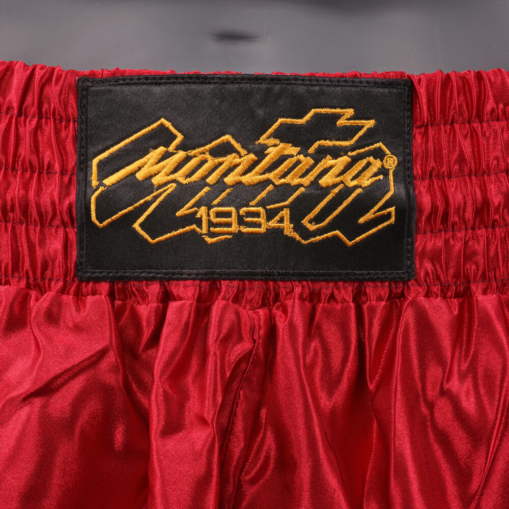 Détail de la ceinture du short de boxe Montana MUAY THAI NewCode Legend : logo Montana 1934 brodé en doré sur la bande élastique bordeaux.