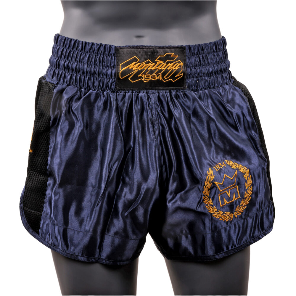 Short de boxe navy Montana MUAY THAI NewCode Poseidon en satin polyester, porté et vu de face, avec la large bande élastique de ceinture et le blason doré.