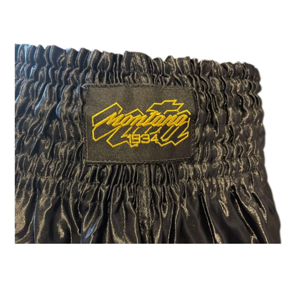 Short de boxe noir MULTIBOX NewCode en satin polyester, coupe classique adaptée au Kick et Muay Thai, confortable et léger.