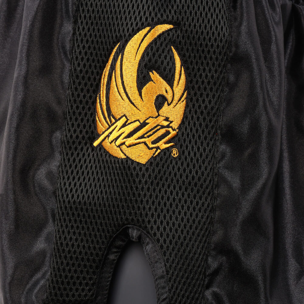Short Muay Thai noir NewCode en satin polyester, avec bande latérale mesh VENTIL’AIR pour une meilleure ventilation, large ouverture et ceinture élastique.