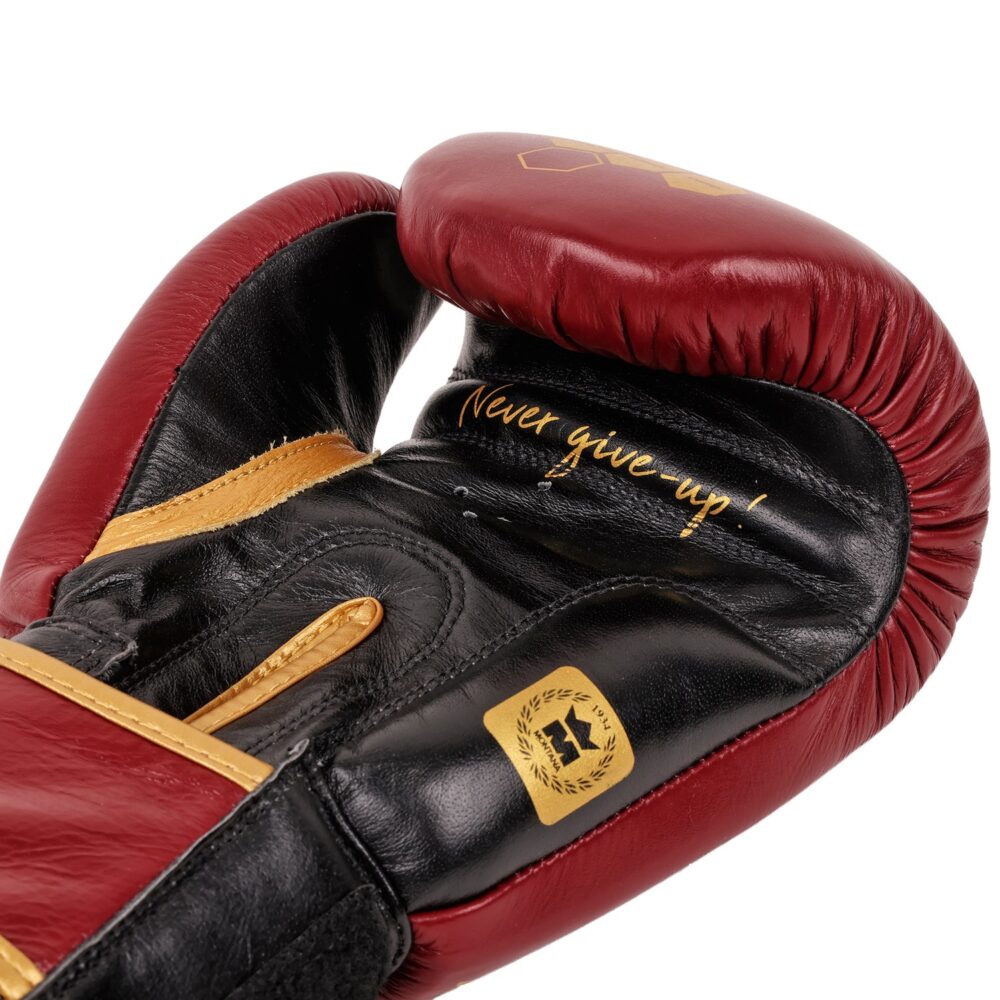 Détail macro du gant de boxe Montana ULTIMATE Legend : intérieur de la manchette bordeaux et noire portant l'inscription dorée « Never give-up » et les surpiqûres or.