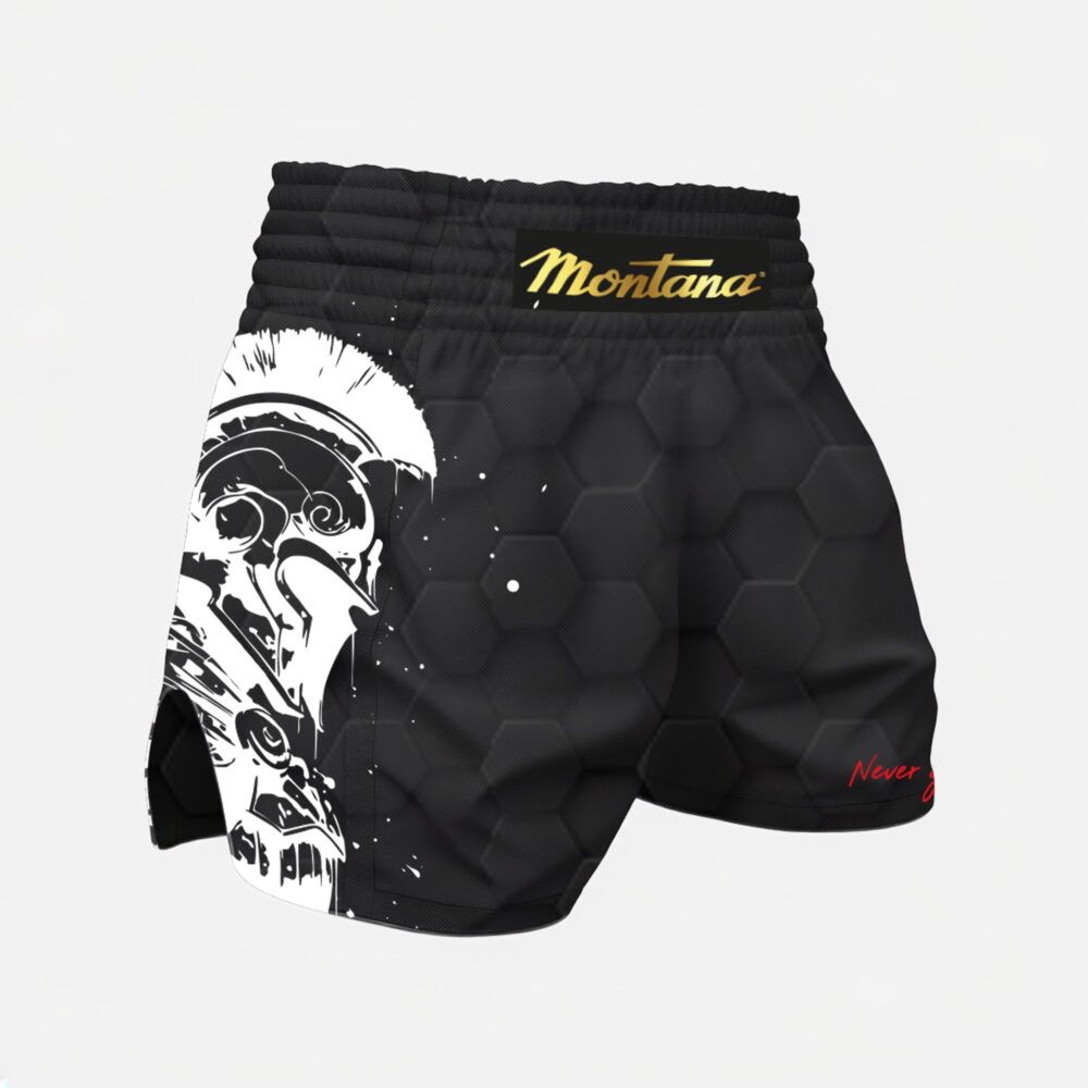 Short de boxe noir Montana MULTIBOX Spartiate vu de profil gauche, avec le casque de guerrier spartiate imprimé en blanc sur le côté et le logo Montana doré à la ceinture.